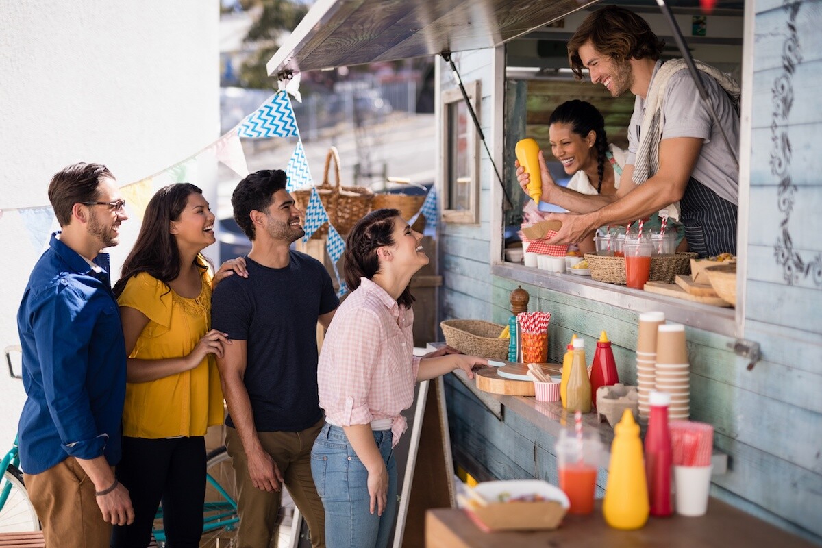 Smiling waiter giving order to customers at counter