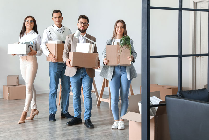 Four Office Employees Moving Boxes