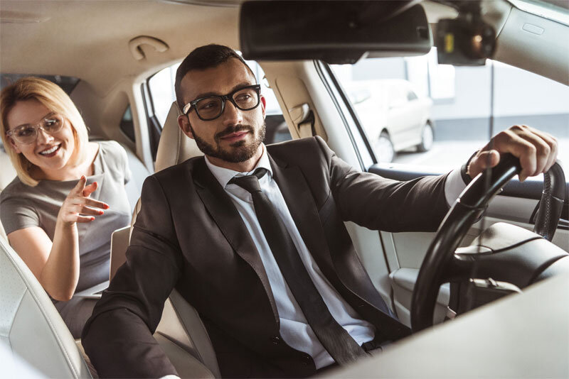 Man in Suit Driving Business Woman in Car