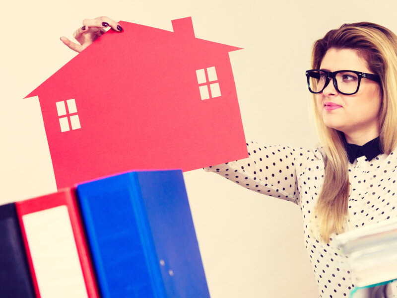 Thining business woman in office holding house