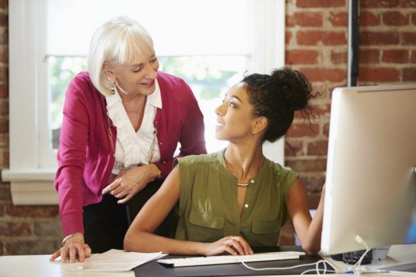 Two Women Working At Computer In Contemporary Office